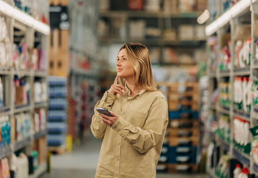 Young woman using phone while shopping at supermarket