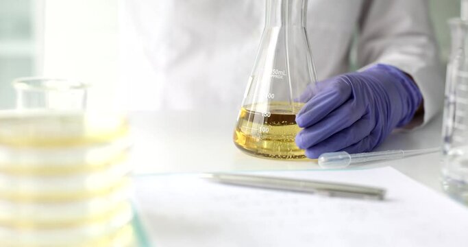 Chemist pours edible oil and petroleum products into flask closeup. Crude oil analysis