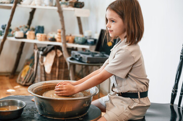 Little girl is learning how to do pottery in the workshop