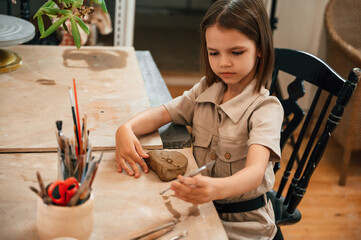 Little girl is learning how to do pottery in the workshop