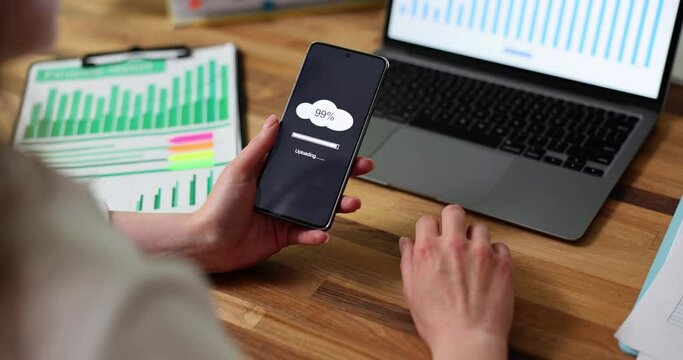 Cloud loading concept on phone screen. Woman is holding phone in hands performing cloud upload