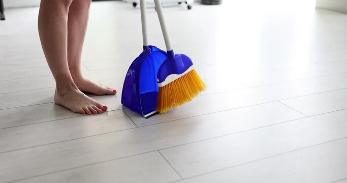 Household routine and closeup of woman with bare feet sweeping floor of house with broom and dustpan. Housewife and house cleaning