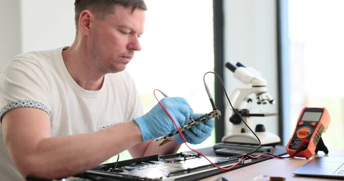 Master checks the condition of laptop circuit board with tester. Experienced engineer working with voltage detector for electronic equipment in service center