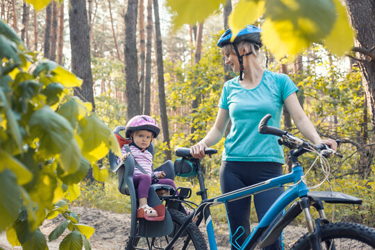 Mom And Baby Ride A Bike In A Summer Pine Forest