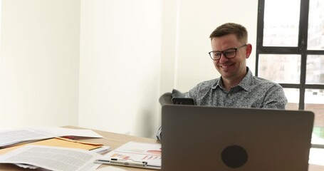 Happy joyful looking at smartphone using online app on gadget. Young man making video call from office talking through virtual conference chat