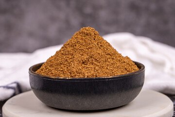 Coriander powder on dark background. Powdered dried coriander in bowl. Spice concept. Close up