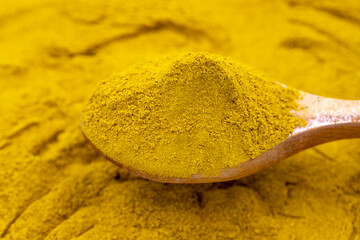 Powdered curry on wooden spoon. Pile of curry powder. close up