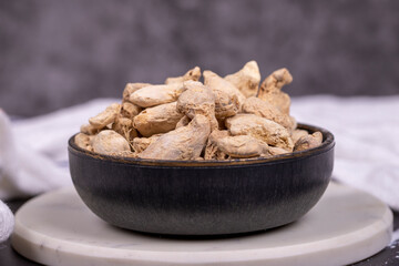 Ginger root on dark background. Ginger root in wooden bowl. Mixture of spices and dried herbs. Spice concept. Close up
