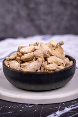 Ginger root on dark background. Ginger root in wooden bowl. Mixture of spices and dried herbs. Spice concept. Close up