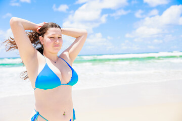 髪の毛を束ねる水着姿の白人女性