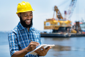 Laughing african american offshore worker with digger and ocean