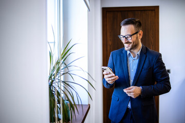 Smiling caucasian businessman checking email on his smart phone.