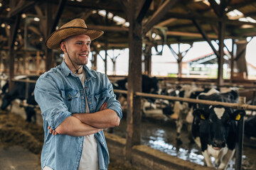 Happy cowboy standing in a stale with cows in it.