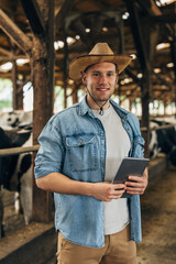 Cowboy standing in a stable with a digital tablet.