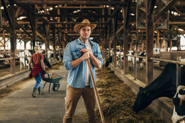 Caucasian farmer is working in a stable and looking at the camera.