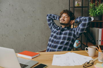 Successful relaxed resting calm tranquil employee business Indian man he wearing casual blue...