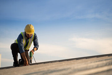 Worker repairing the roof on a construction site. Electric drill used on roof, Roof construction concept. - 612255428