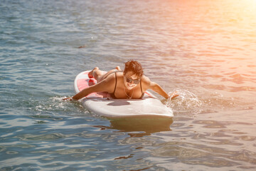 Woman sup sea travel. Sports girl on a surfboard in the sea on a sunny summer day. In a black...
