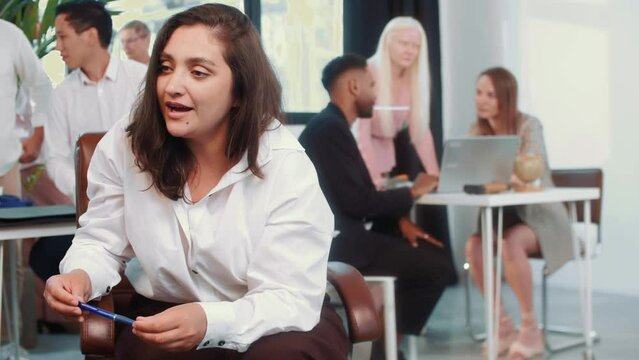 Portrait of confident young female start up owner pitching idea to client and smling in light office setting