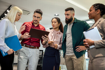 A business team is standing in a modern office and having a discussion