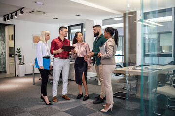 A business team is standing in a modern office and having a discussion