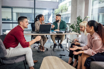 Office colleagues having discussion during meeting in conference room. Group of men and women in modern office.