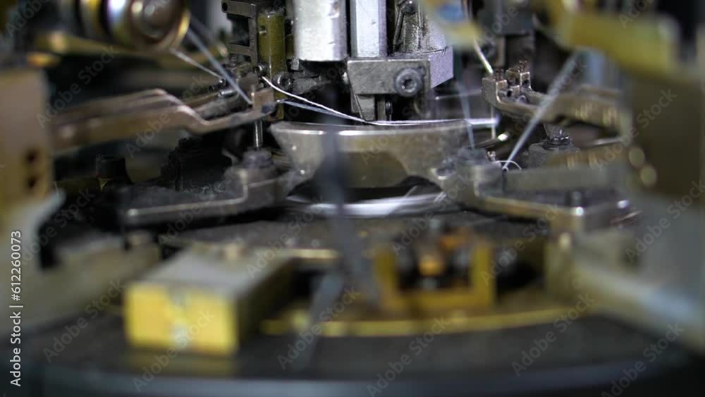 Poster the process of manufacturing of socks on a loom - close-up shot of spools with white thread at rewin