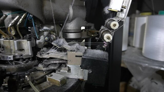 The process of manufacturing of socks on a loom - Close-up parts of the machine with threads, the Production process in a garment factory,