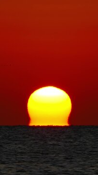 Sun over sea sunrise - shot with telephoto lens, timelapse. Vertical video