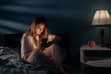 Young woman awake late at night using smartphone for chatting and sending messages. Internet addiction. Mobile abuse and insomnia concept