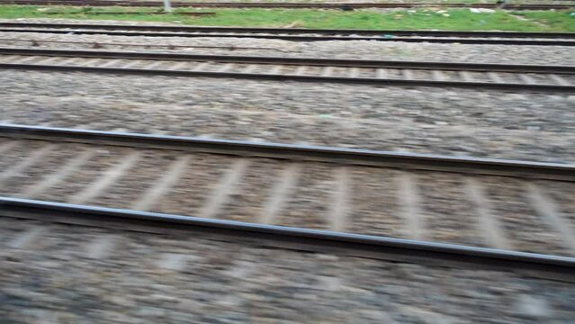 Parallel tracks running along a speeding Train with trees and electric poles leaving behind. Northern Indian Railways. India.