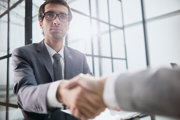 Man shaking hands with partner over office desk