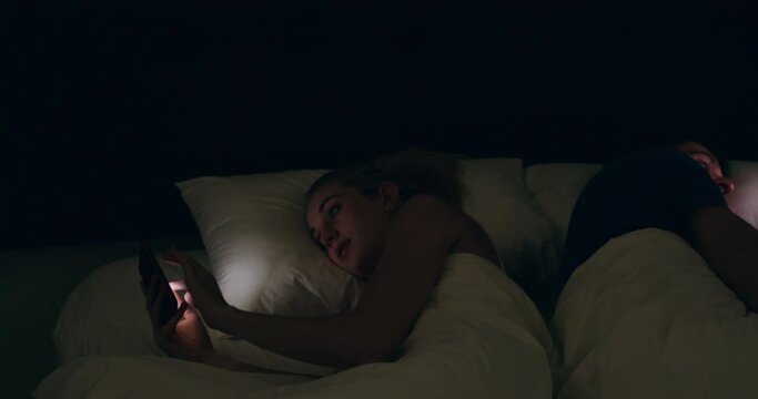 Phone addiction, bed and couple online, insomnia and social media with marriage problem and light in face. Cellphone, man and woman in bedroom reading post, meme or mobile app on internet in dark.