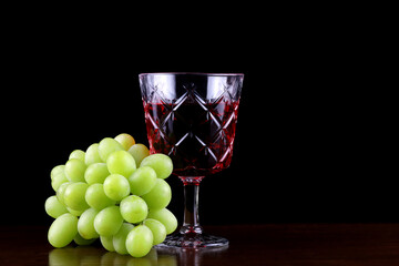 Glass of Wine with Grapes on a Wooden Surface with Black Background