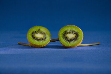 Kiwi halves and stems on a blue background close-up