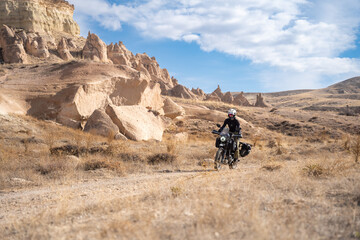 Female motorcyclist riding in between special rock formations in Cappadocia, Turkey
