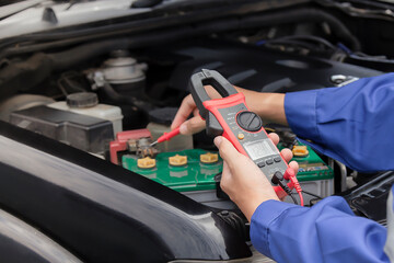 technician uses multimeter voltmeter to check voltage level in car battery. Service and Maintenance car battery.
