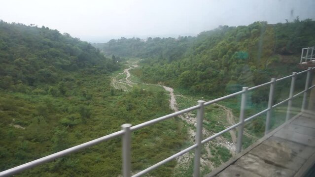 View through a train window glass. A train passing through a bridge over a dry river valley in Katra district of Jammu and Kashmir to reach Mata Vaishno Devi Railway Station. India
