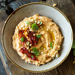 bowl of hummus with basil and sun dried tomatoes on the table