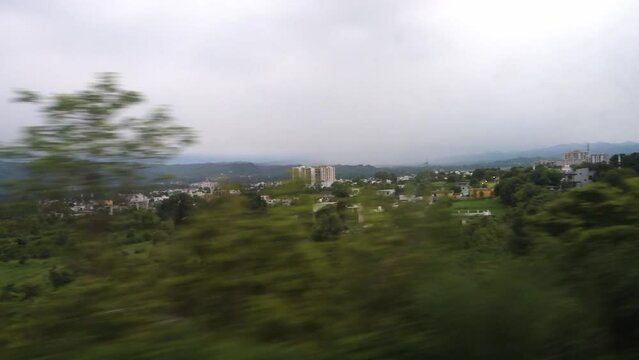 Outside valley and distant cityscape view through the window of a moving train while traveling to Mata Vaishno Devi Shrine. Katra Express Jammu And Kashmir.