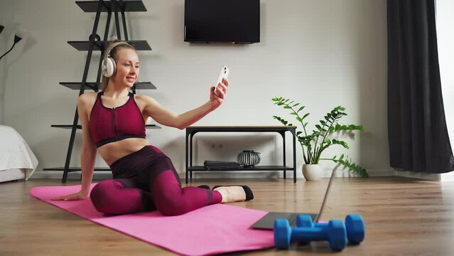 Woman girl in sportswear during a home workout makes a selfie in social networks. Blogger training