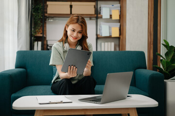 Business woman using tablet and laptop for doing math finance, tax, report, accounting, statistics, and analytical research concept on sofa in home office.