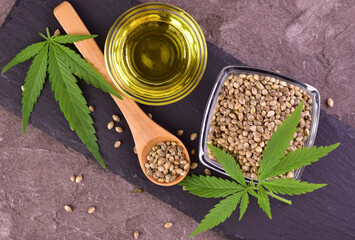 Hemp oil and hemp seeds on a dark wooden background.Lei flat.
