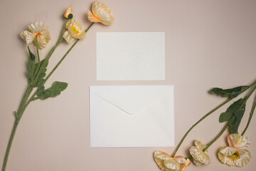 A white blank letter and envelope with flowers over the light background. 