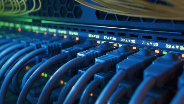 Close-up Shot of Datacenter Network Switch full of Plugs and Connectors in Rack Cabinet. Internet Ports with Blinking Lights on Industrial Router. High Performance Network Equipment.