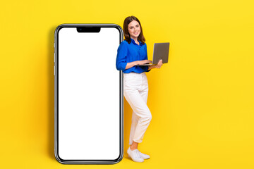 Full length photo of dreamy sweet lady wear blue shirt typing modern device empty space isolated yellow color background