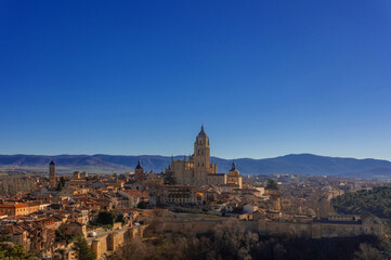 Fototapeta na wymiar Cityscape of Segovia, Spain, with the mixture of medieval and Romanesque architecture and its majestic mountains in the background