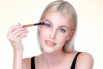 Beautiful personable girl with flawless applying eye shadow makeup with eyeliner brush. Cosmetic...
