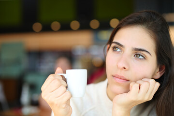 Pensive serious woman holding coffee in a bar