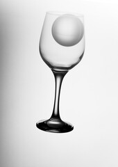 A wine glass with an ice ball. Clear reflections. Separated from background. Minimalistic drinks. Glass ball in a vine glass on white background. Black and white high contrast. 